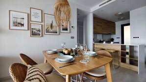 A modern dining area with a wooden table set for four, surrounded by wicker chairs. - SUNSET WAVES fresh apartments (Benidorm)