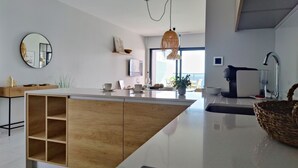 A modern kitchen with a central island, a hanging light fixture, and a large window providing natural light. - SUNSET WAVES fresh apartments (Benidorm)