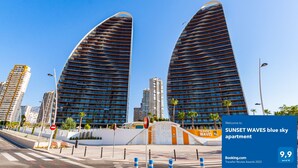 A modern building with a curved facade, surrounded by other high-rise buildings. - SUNSET WAVES blue sky apartment (Benidorm)