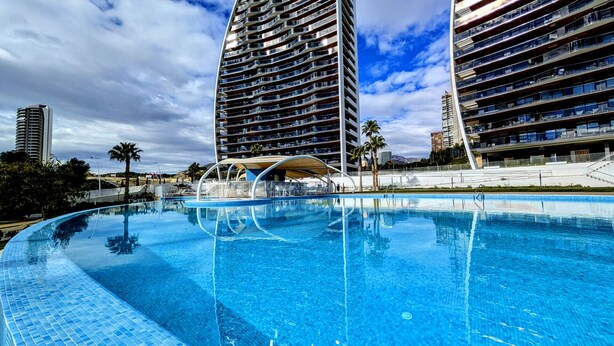 Ett modernt hotell med pool, flera balkonger och utsikt över det omgivande området.