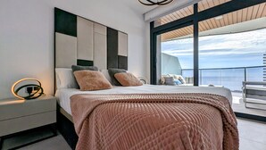 Un dormitorio moderno con una cama grande, una mesita de noche y vistas al mar.