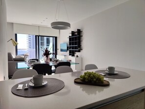 A modern dining area with a glass table, black chairs, and a central vase with flowers. - SUNSET WAVES sea & light apartments (Benidorm)