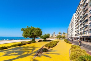 A coastal promenade with a yellow pathway, palm trees, and a view of the sea and buildings. - SUNSET WAVES sea & light apartments (Benidorm)
