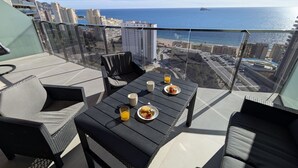 Un balcón con una mesa dispuesta para el desayuno, con vistas a la ciudad y al mar.
