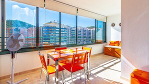 A balcony with a table and chairs, a fan, and a view of buildings. - BALCÓN DEL MAR sunny apartment (Benidorm)