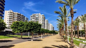 Een woonwijk met meerlaags appartementencomplexen, een verharde looppad en palmbomen.