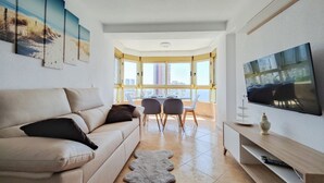 A modern living room with a sofa, a flat-screen TV, and artwork on the wall. - GERONA sea view apartments (Benidorm)