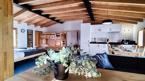 Een gezellig interieur van een blokhut met houten plafond, een eethoek, een keuken en een slaapgedeelte met een stapelbed.