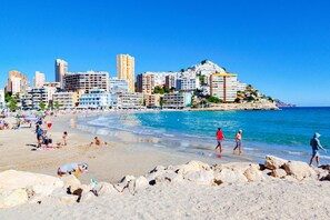A beach with a cityscape in the background, featuring a variety of buildings and a clear blue sky. - BALCÓN DEL MAR Ocean View Apartment (Benidorm)