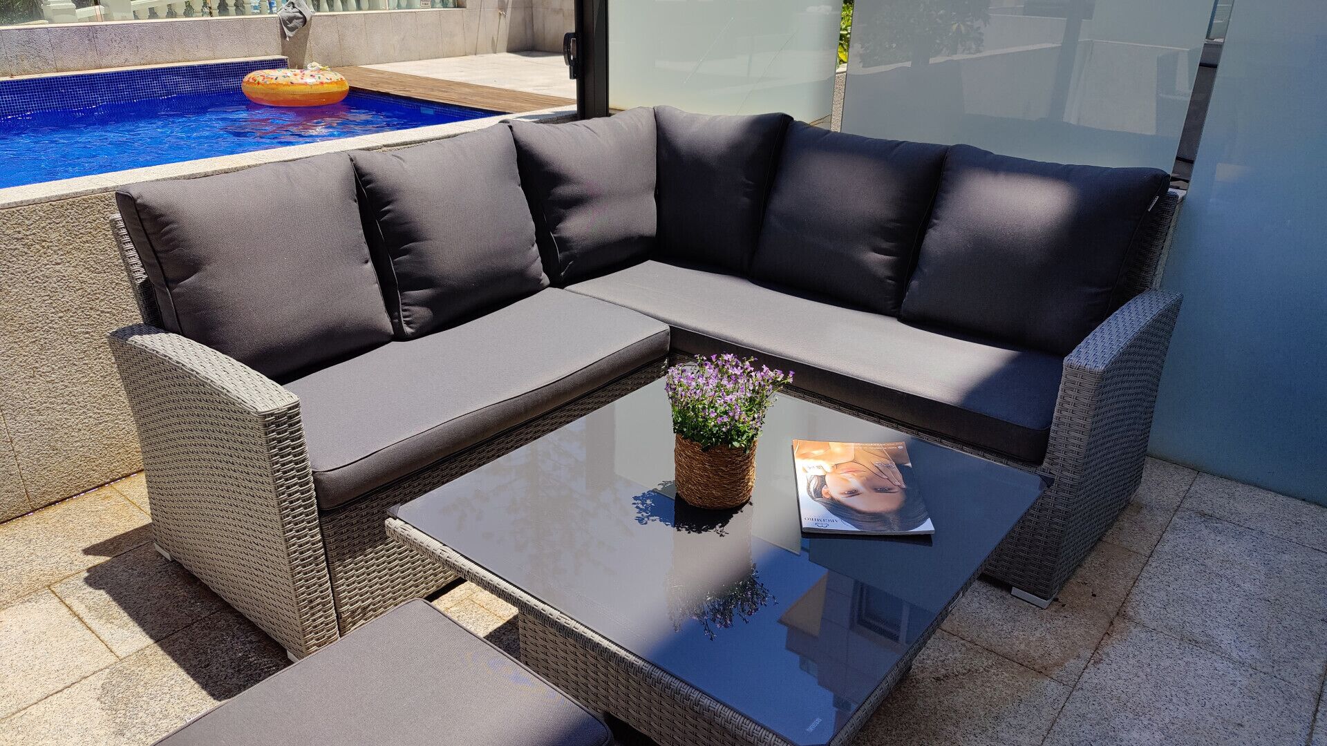 Un canapé modulable avec des coussins, une table basse en verre et un fauteuil en osier.