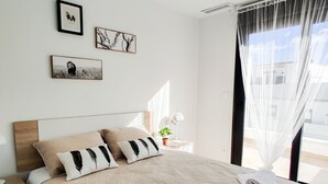 Une chambre à coucher avec un grand lit, une table de chevet avec une lampe et des œuvres d’art encadrées accrochées au mur.