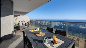 A balcony with a table set for breakfast, overlooking a cityscape and the sea. - SUNSET CLIFFS sea & sky apartments (Benidorm)