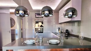 A modern kitchen with a central island, pendant lighting, and a view into the dining area. - ESTRELLA design & beach apartment (Benidorm)