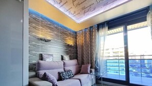 A modern living room with a sofa, a glass coffee table, and a view of the city through large windows. - ESTRELLA design & beach apartment (Benidorm)