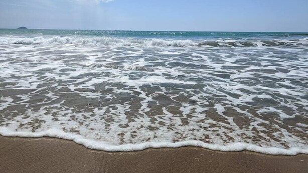 A beach with waves gently lapping onto the shore. - ESTRELLA design & beach apartment (Benidorm)