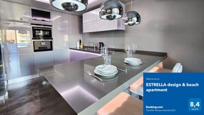 A modern kitchen with a central island, pendant lighting, and a view of the city. - ESTRELLA design & beach apartment (Benidorm)