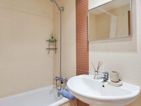 Une salle de bain avec une baignoire, un lavabo, un miroir et une douche.