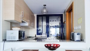 A modern kitchen with a microwave, toaster, and coffee maker. There is a dining area with a table and chairs, and a decorative bowl on the table. - ESTRELLA honey apartment (Benidorm)