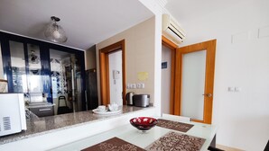 A modern kitchen with a glass dining table, a coffee maker, and a refrigerator. - ESTRELLA honey apartment (Benidorm)