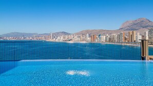 Une piscine avec une vue sur la ville et des montagnes en arrière-plan.