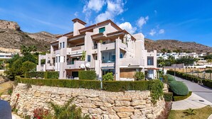 A modern multi-story house with a stone facade, multiple balconies, and a landscaped garden. - Jardin Sweet Apartment (Finestrat)