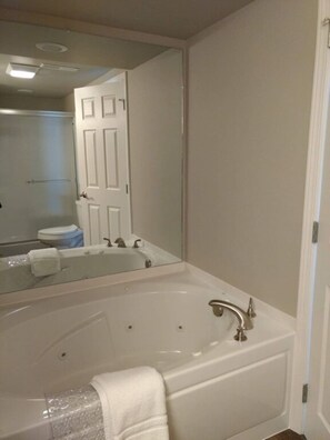 Un bagno con una vasca da bagno ampia, uno specchio e una porta.