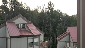 A cabin with a balcony, a red roof, and a view of the surrounding forest. - 3BR/2BA Stand-alone condo. Close to downtown (Gatlinburg)