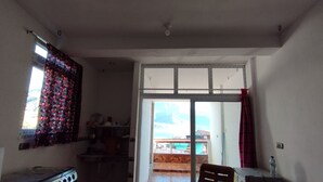 Een kleine, compacte kamer met een kitchenette, een enkele stoel en een bed.