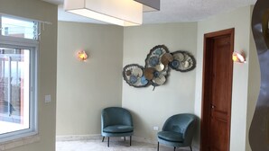 A room with two teal chairs, a decorative wall piece, a wooden door, and a large light fixture. - Cabrera oceanview villa (Cabrera)
