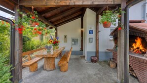 An outdoor covered patio with wooden benches, hanging flower baskets, a fire feature, and a brick oven. - 2 BR House By The Creek Near Plitvice Lakes (Plitvicka Jezera)