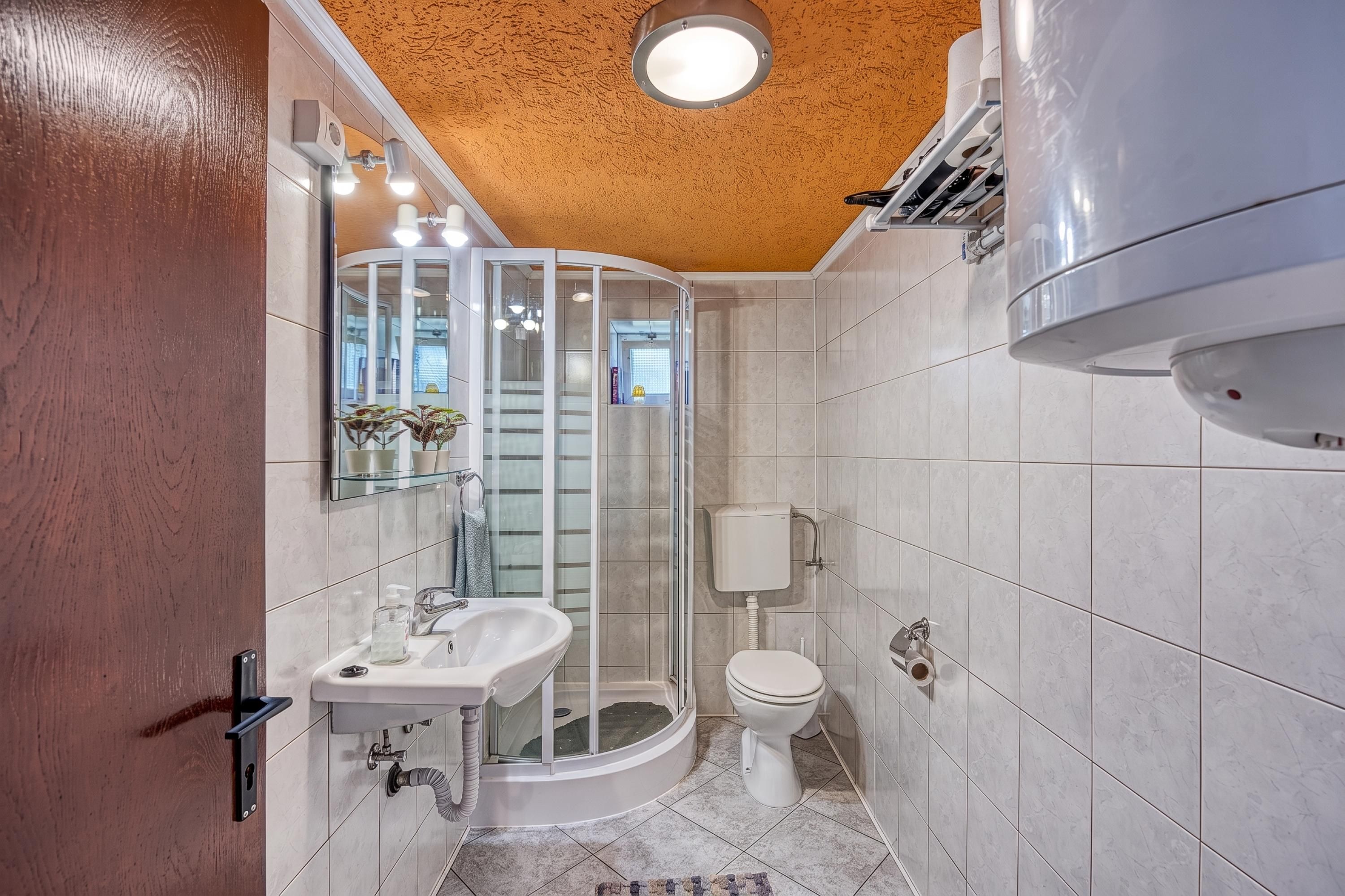 Un baño moderno con cabina de ducha de vidrio, un lavabo blanco y un inodoro.