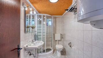Un baño moderno con cabina de ducha de vidrio, un lavabo blanco y un inodoro.