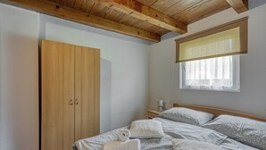 A bedroom with a wooden wardrobe, a bed with patterned bedding, and a window with blinds. - 2 BR House By The Creek Near Plitvice Lakes (Plitvicka Jezera)