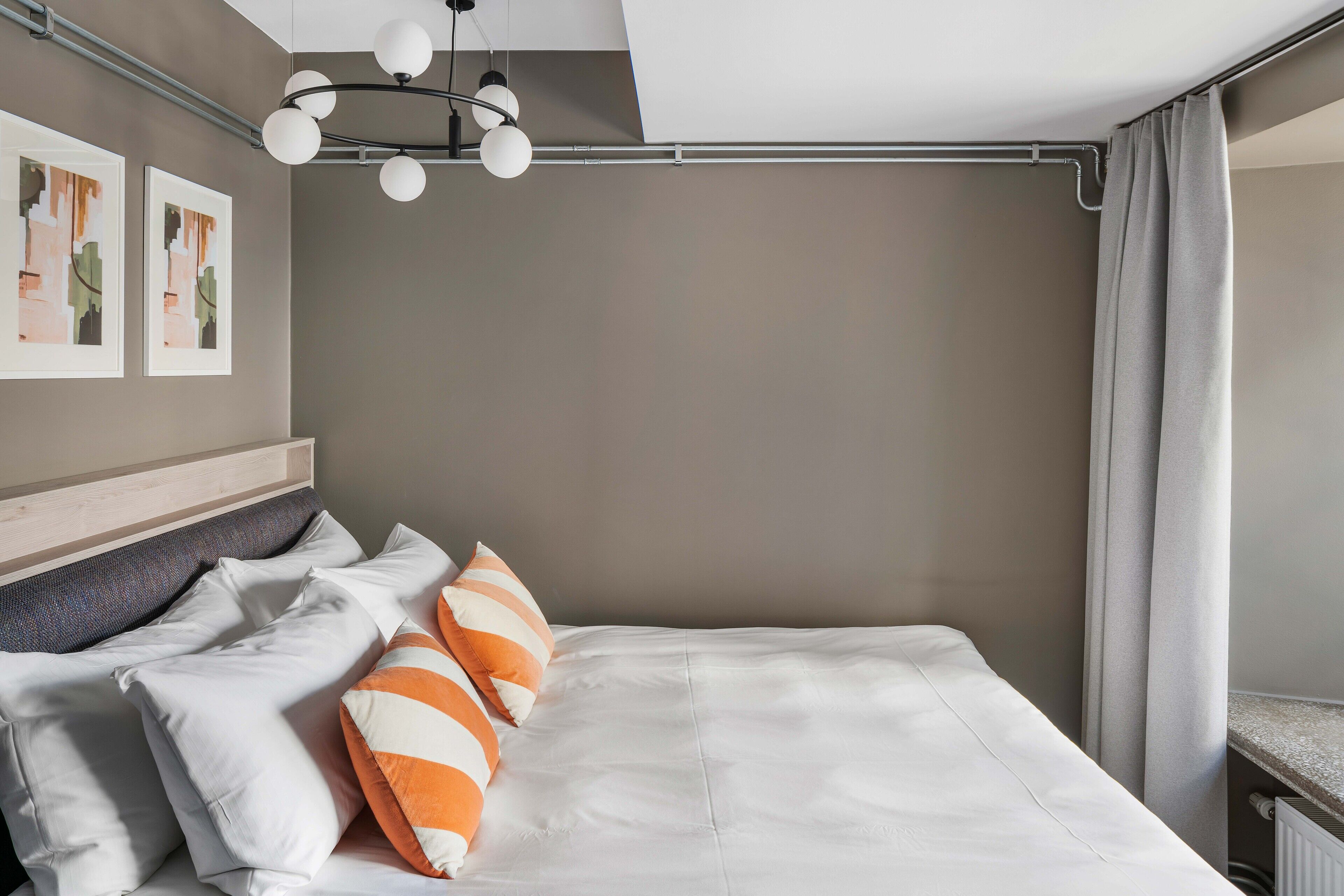 A modern bedroom with a bed, pillows, and a ceiling light fixture.
