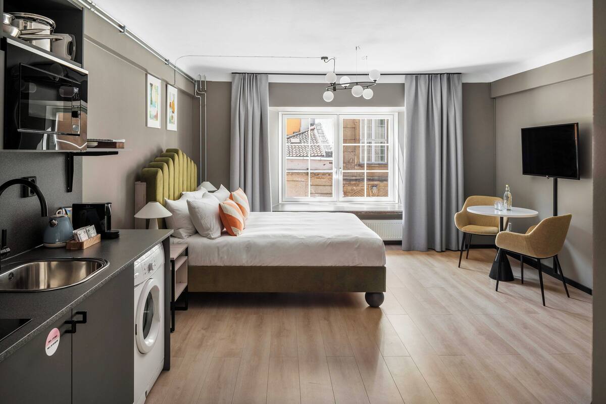 Une chambre d’hôtel moderne équipée d’un lit, d’un petit coin cuisine, d’une table à manger et d’un téléviseur.