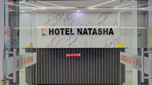 A reception desk with a marble wall and a sign that reads "HOTEL NATASHA". - Itsy Hotels Natasha, Vesu, Surat (Surat)