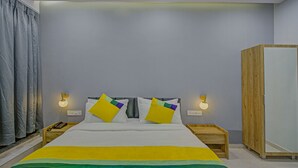 A bedroom with a bed, two bedside tables, a wardrobe, and a curtain. - Itsy Hotels Natasha, Vesu, Surat (Surat)