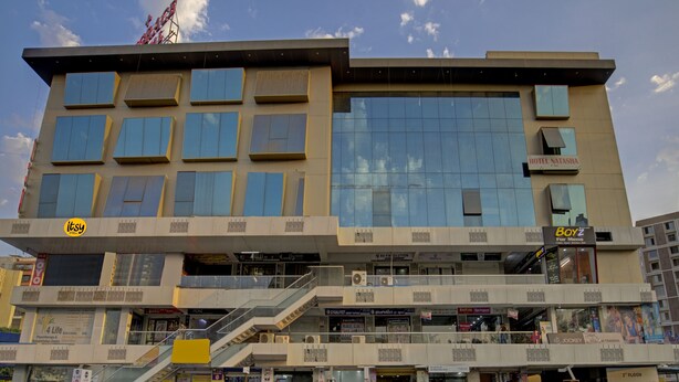 A multi-story building with a modern architectural design, featuring a mix of glass and metal facades. - Itsy Hotels Natasha, Vesu, Surat (Surat)