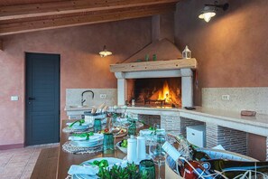 A dining area with a fireplace, wooden ceiling, and a table set for a meal. - Villa Azur – Private pool, wellness, and spacious garden (Muntic)