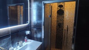 A modern bathroom with a large mirror, a glass-enclosed shower, and a white sink. - Exclusive room with bathroom - on Metro A line (Roma)