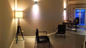 A conference room with a carpeted floor, a desk, two chairs, and a floor lamp. - Exclusive room with bathroom - on Metro A line (Roma)