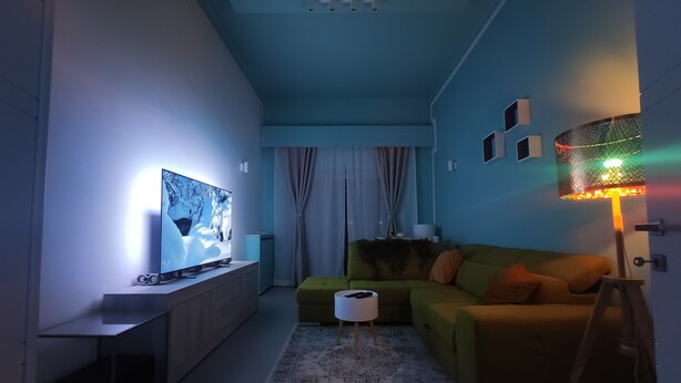 A modern living room with a flat-screen TV, a green sofa, a patterned rug, and a floor lamp. - Exclusive room with bathroom - on Metro A line (Roma)