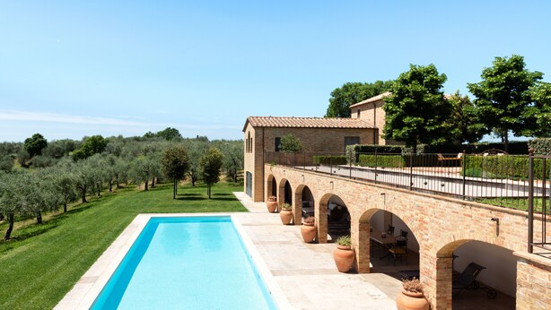 A swimming pool with a brick patio and arches, surrounded by a well-maintained lawn and olive trees. - Recently restored Villa in Tuscany, sleeps 12, sw.pool,  gym, big garden. (San Giovanni d' Asso)