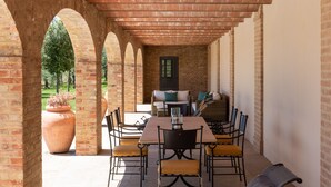 An outdoor patio with a brick archway, a table with chairs, and a sofa with cushions. - Recently restored Villa in Tuscany, sleeps 12, sw.pool,  gym, big garden. (San Giovanni d' Asso)