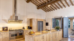 A modern kitchen with a central island, stainless steel appliances, wooden cabinets, and a stone countertop. - Recently restored Villa in Tuscany, sleeps 12, sw.pool,  gym, big garden. (San Giovanni d' Asso)