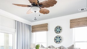 Un dormitorio con una cama grande, un banco de madera, un ventilador de techo y vistas al exterior.