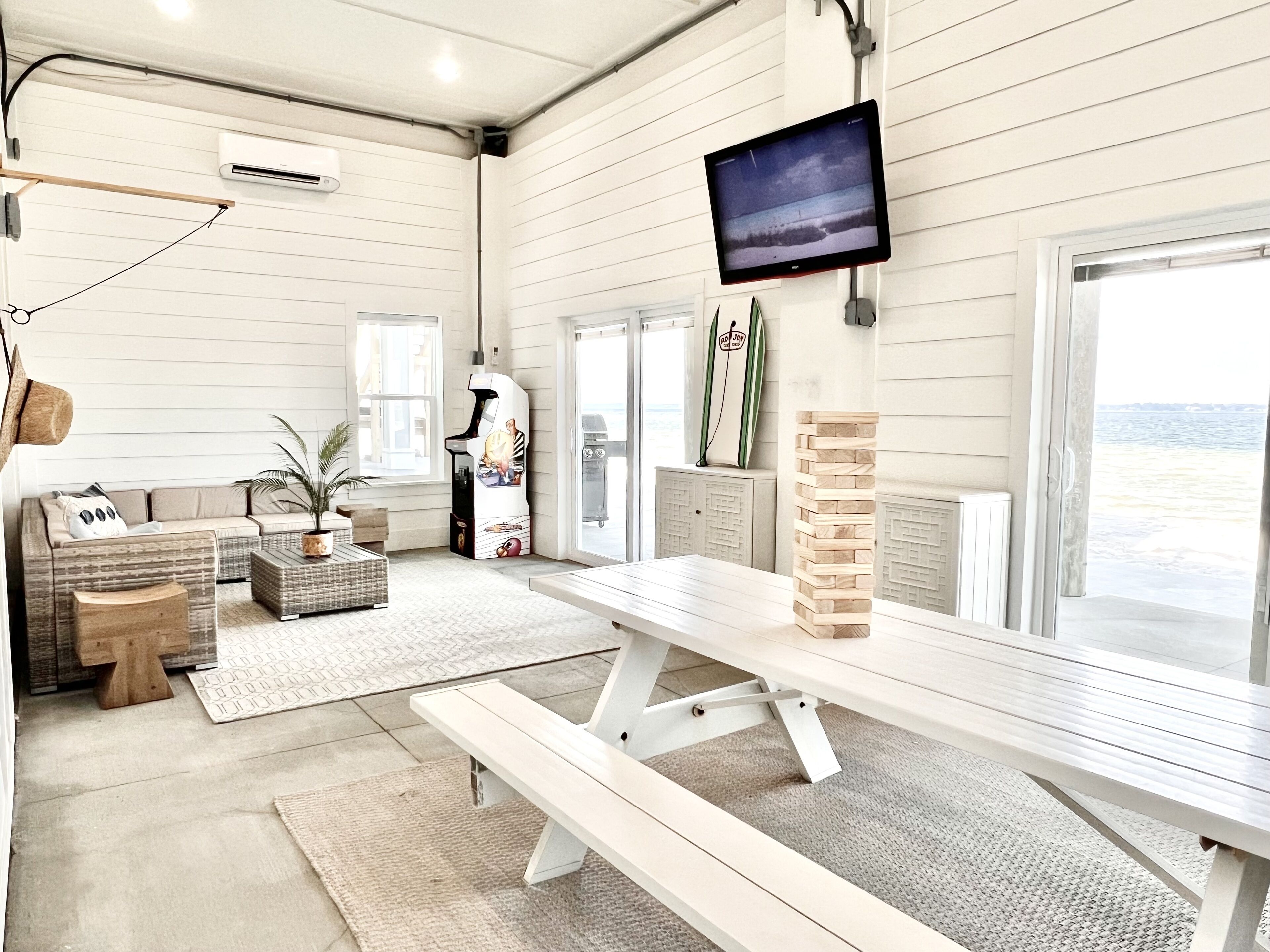 A beach-themed room with a sofa, a coffee table, a TV, and a view of the ocean.