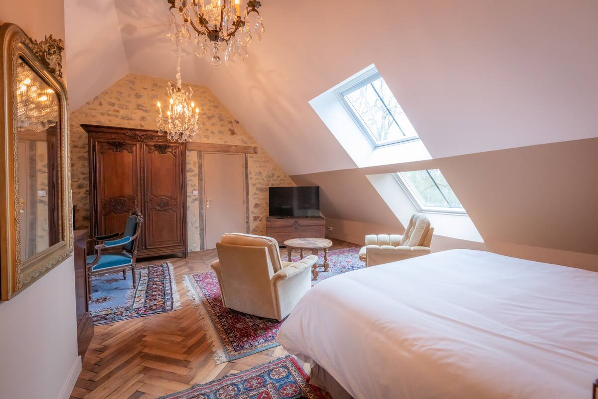 Ein Schlafzimmer mit einem großen Bett, einer Kristallleuchter, einem Fernseher und einem Oberlicht.