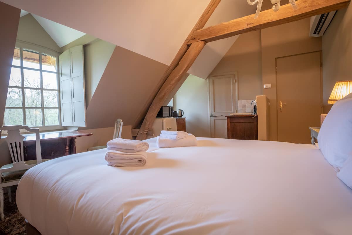Ein Schlafzimmer mit einem großen Bett, einem Schreibtisch, einem Stuhl und einer Küchenzeile.