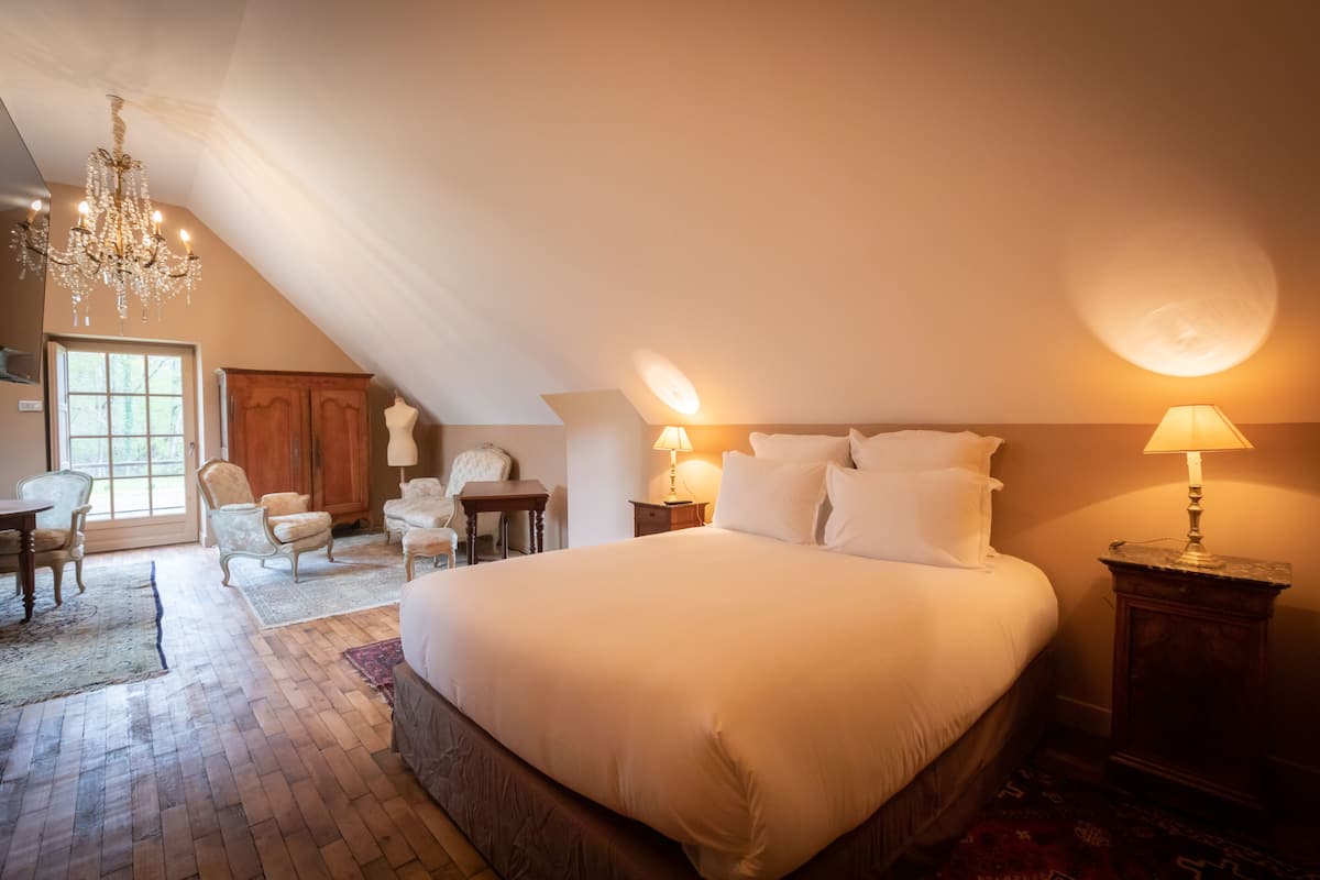 Ein Schlafzimmer mit einem großen Bett, einer Chandelüster und einem Fenster.